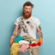 chico con barba lleva mucha ropa sucia de pintura
