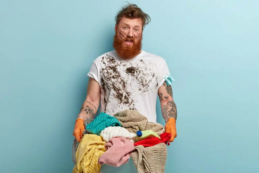 chico con barba lleva mucha ropa sucia de pintura