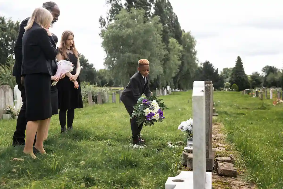 familia pone flores en una tumba tras el entierro