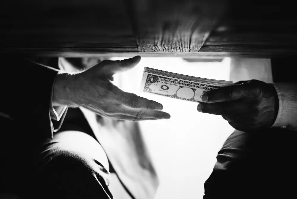 manos bajo mesa pasando dinero