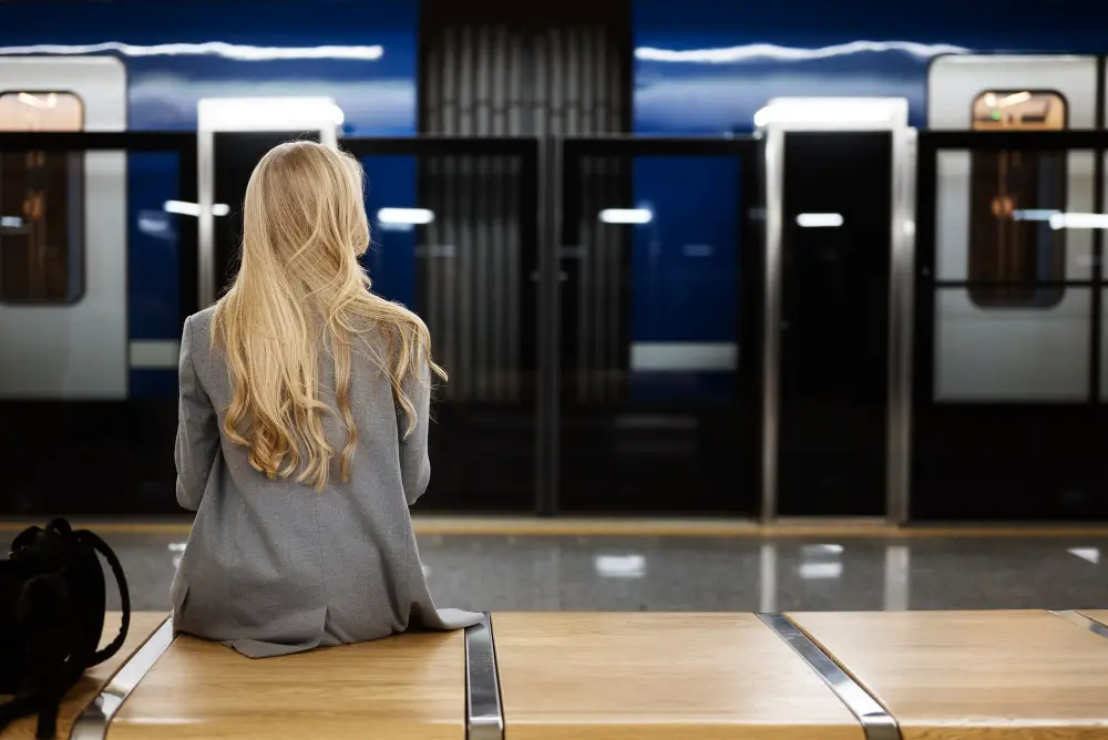 mujer esperando sentada en estación trenes