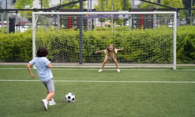 niño tira gol contra niña portería futbol
