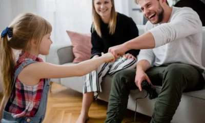 padre sentado sofa choca puño con hija y mujer detras
