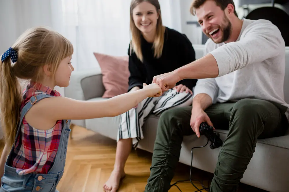 padre sentado sofa choca puño con hija y mujer detras