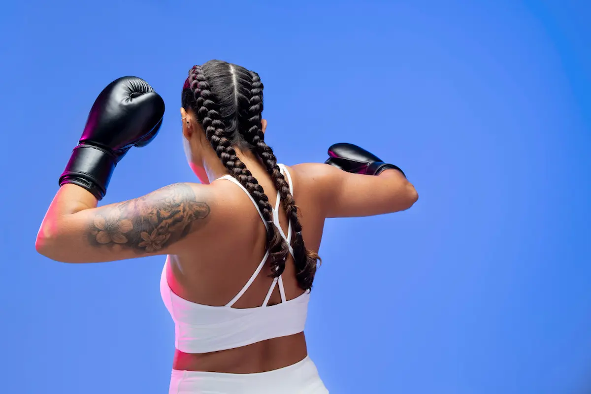 una boxeadora con tatuaje golpeando desde detrás