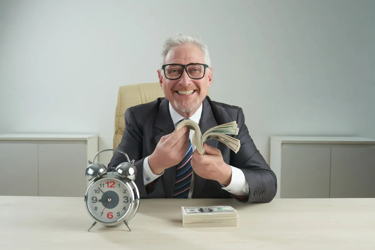 anciano cuenta dinero feliz sentado en escritorio