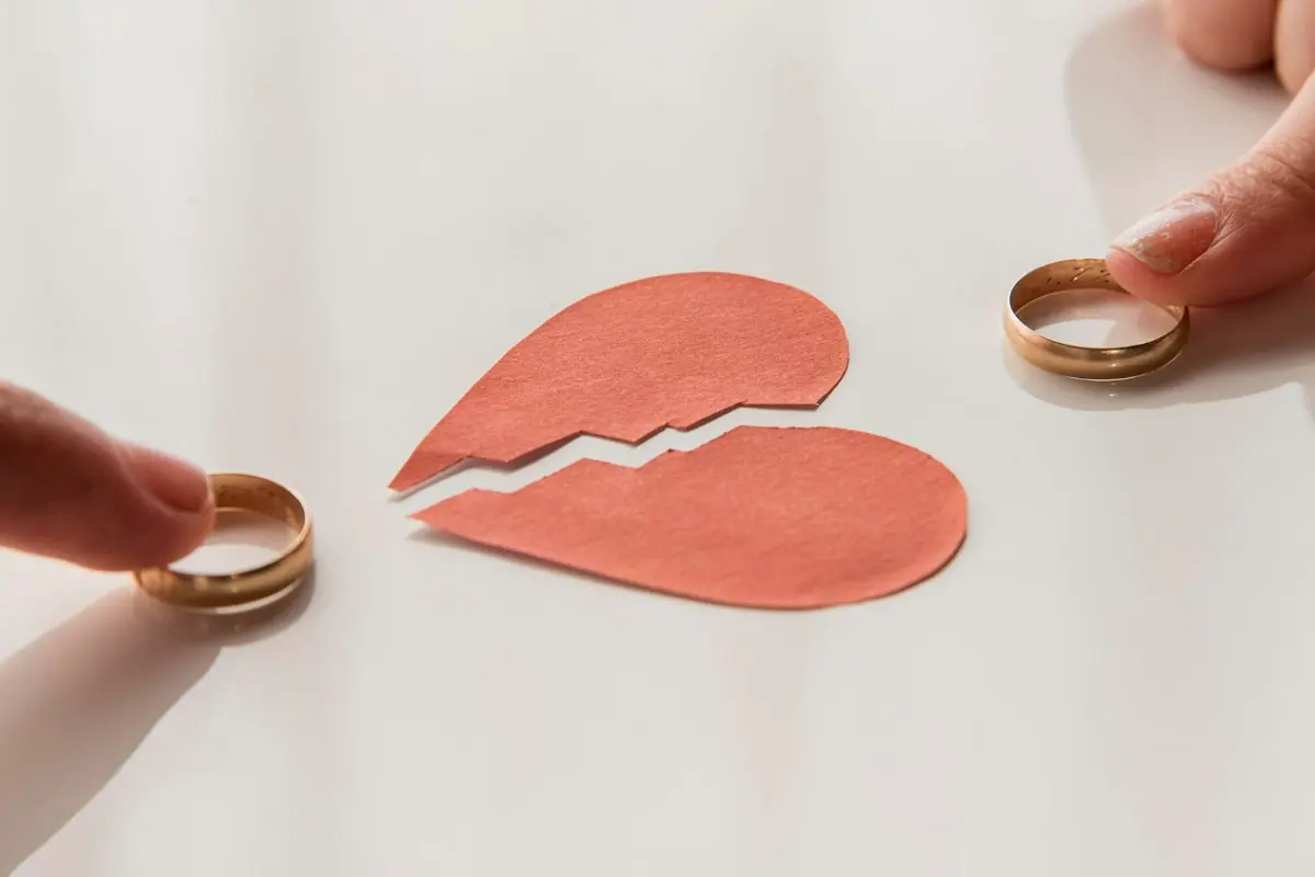 dedos de dos novios con anillos corazon roto