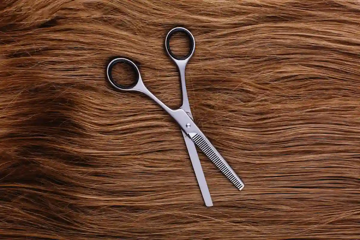 unas tijeras apoyadas sobre pelo de mujer