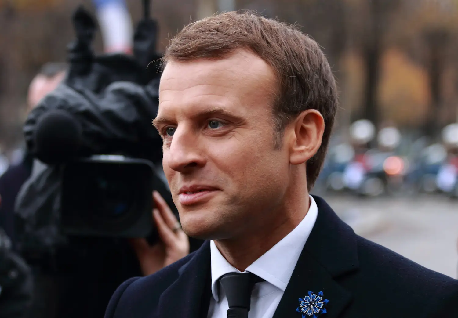 Emannuel Macron sonrie con su traje en la calle