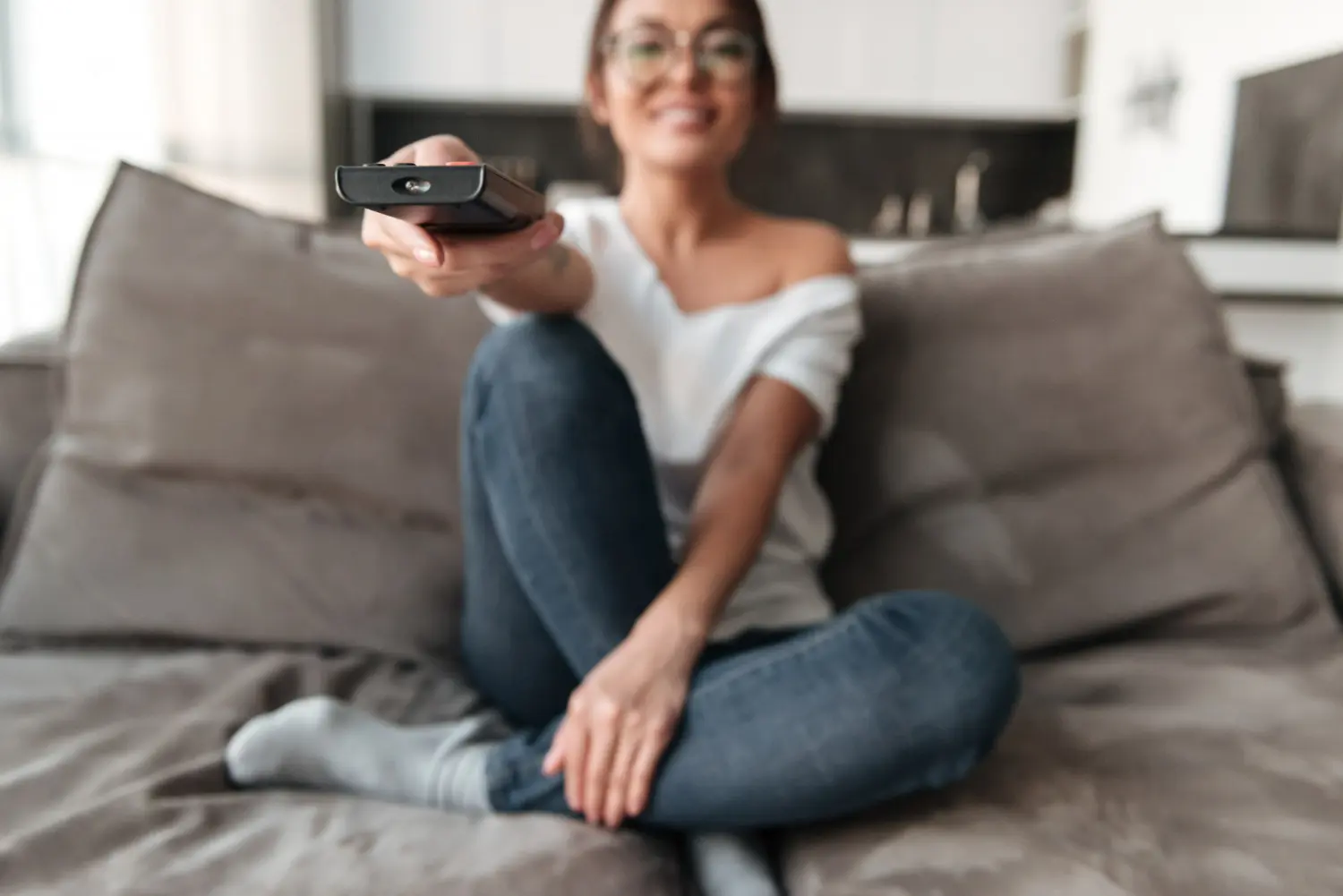 chica sentada mira tv con mando en mano