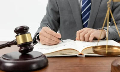 juez escribe delante libro y balancin