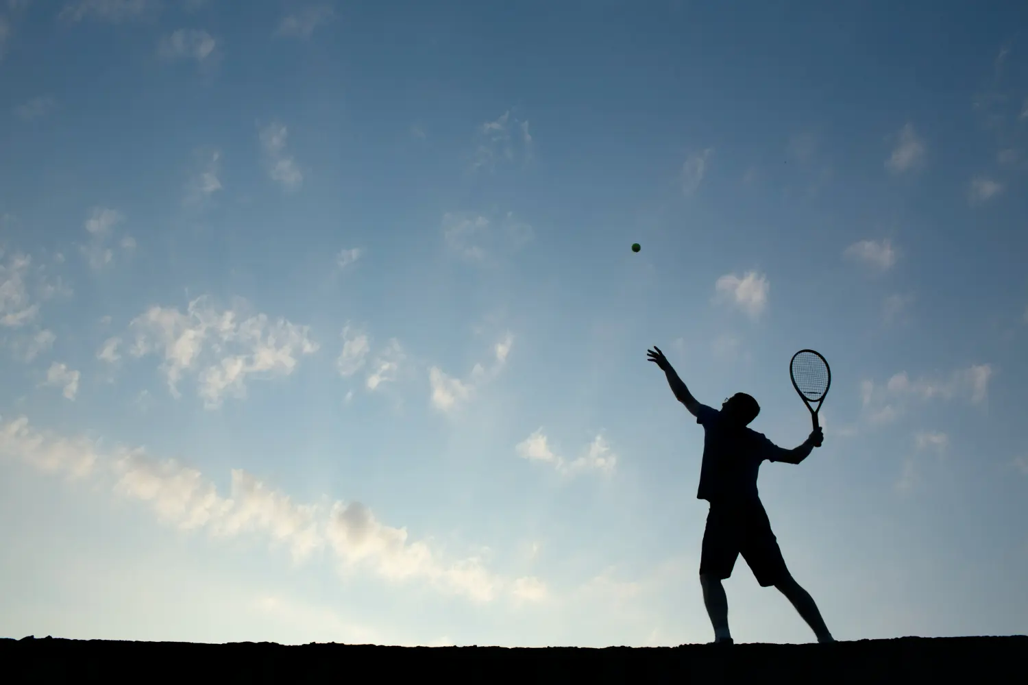jugador de tenis saca debajo del cielo