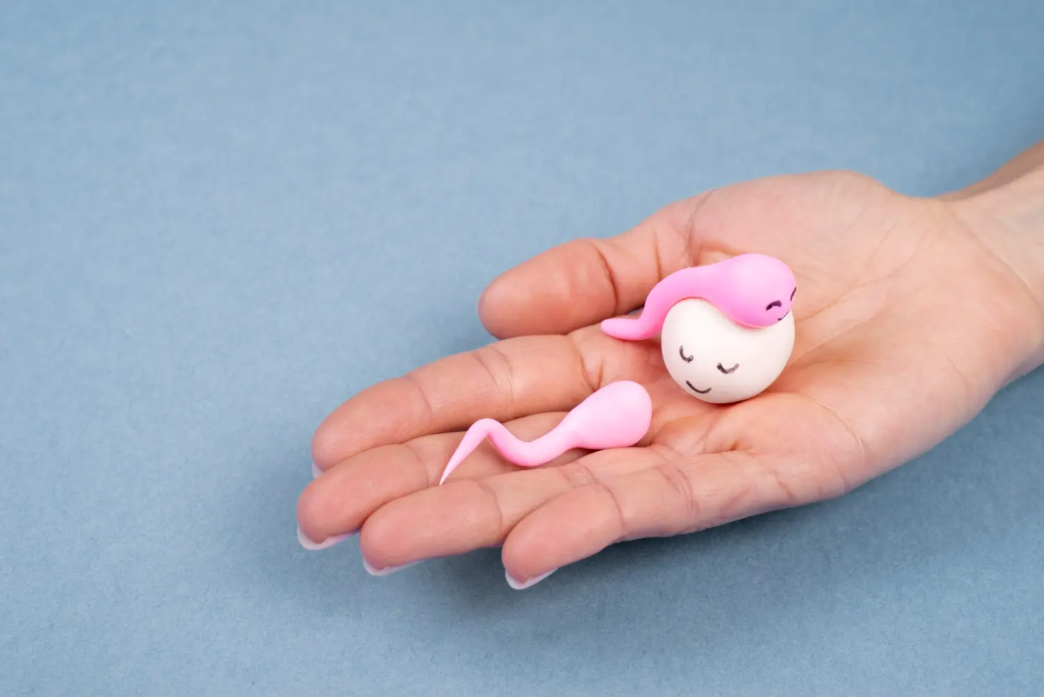 mano con piccolo ovulo e due pupazzetti rosa