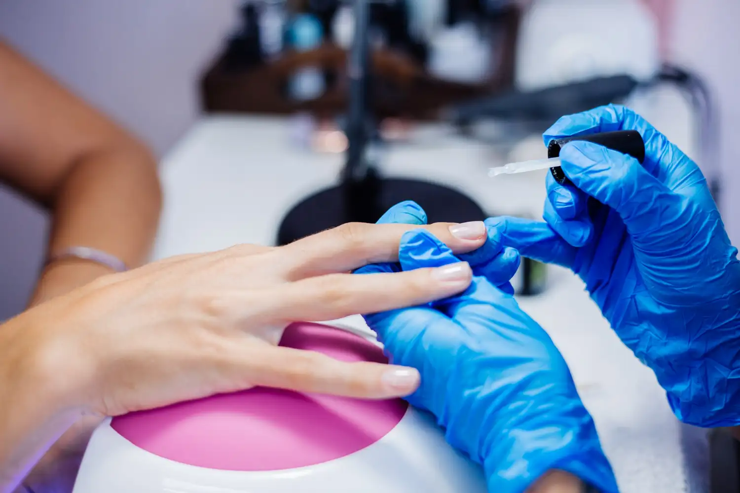 mujer pintando uñas de gel a clienta