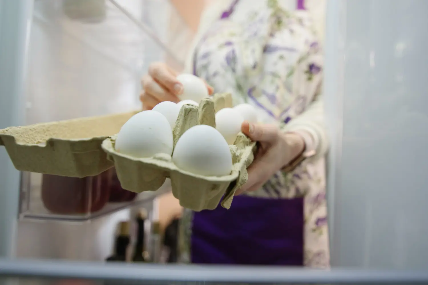 mujer saca huevos de nevera