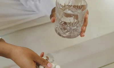 Blíster de comprimidos y vaso de agua sobre mesa, luz cálida