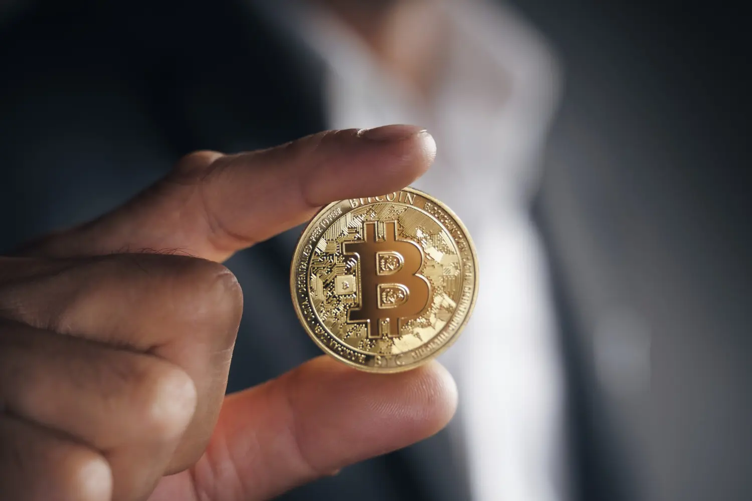 hombre en traje tiene bitcoin en dos dedos