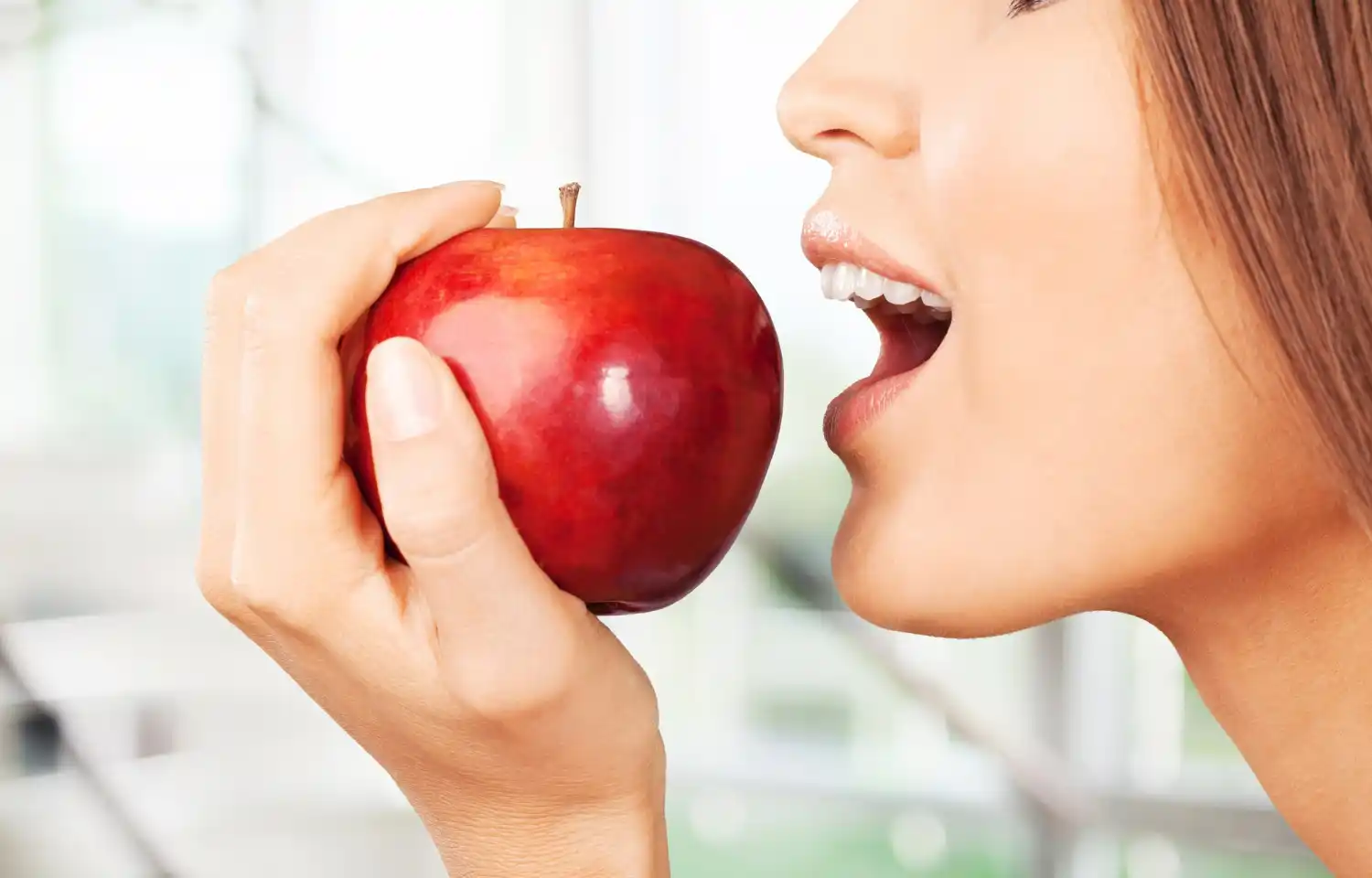 chica mordiendo una manzana roja