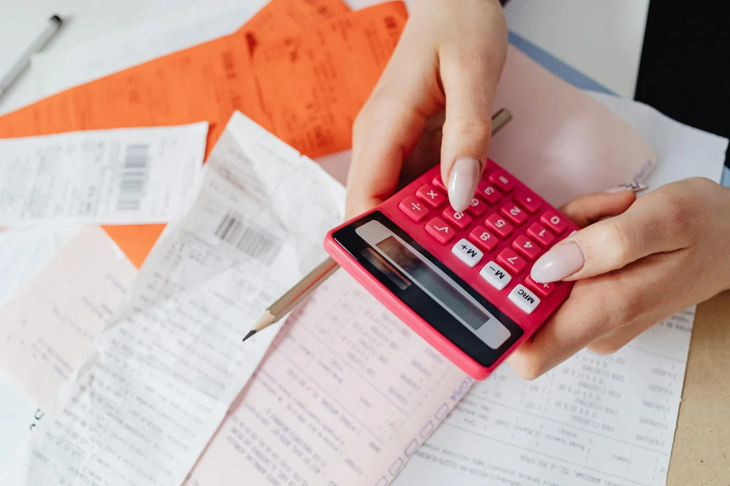 Persona revisando una factura de electricidad y una calculadora para entender porque ha subido el precio de la luz en casa.