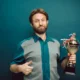 Un hombre sosteniendo un trofeo mientras se recuerda la frase no llores porque terminó sonríe porque sucedió en un contexto de despedida y gratitud.