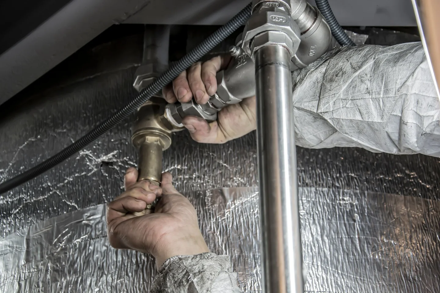 Plumber fixing pipes for article about por que entra aire en las tuberías de agua