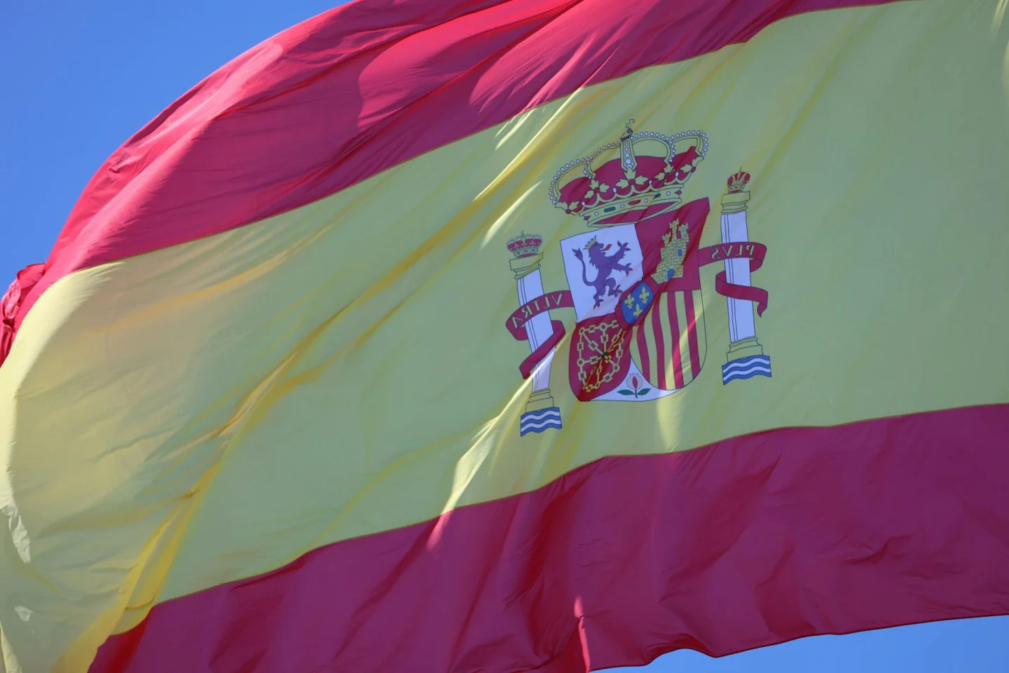 Bandera de España ondeando para ilustrar porque el himno de españa no tiene letra en un contexto de símbolo nacional y ceremonia
