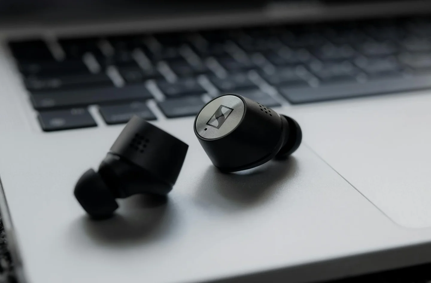 Imagen de unos wireless earbuds junto a un portátil para ilustrar porque no se conectan los auriculares bluetooth