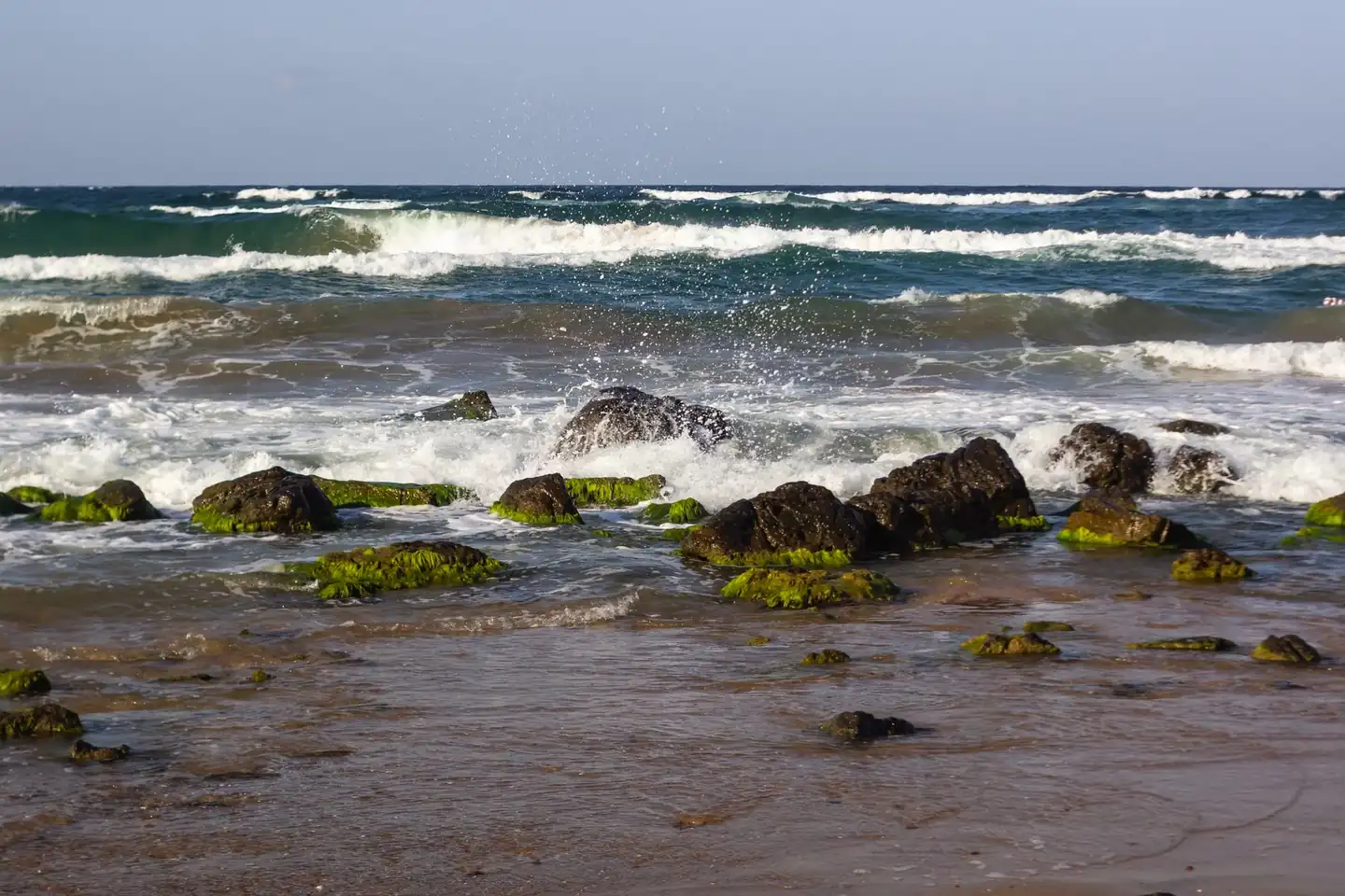 Fotografía de breaking waves beach para ilustrar por qué las olas rompen antes en unas playas en un paisaje costero con oleaje visible.