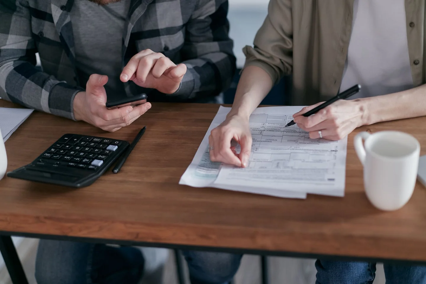 Amigos usando una calculadora para entender cómo repartir gastos de vacaciones entre amigos durante un viaje compartido.
