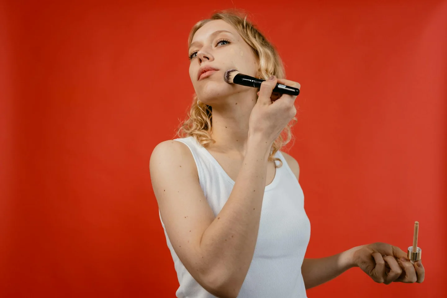 Una mujer aplicando base de maquillaje para ilustrar qué maquillaje aguanta mejor el sudor en un rostro de aspecto natural y duradero.