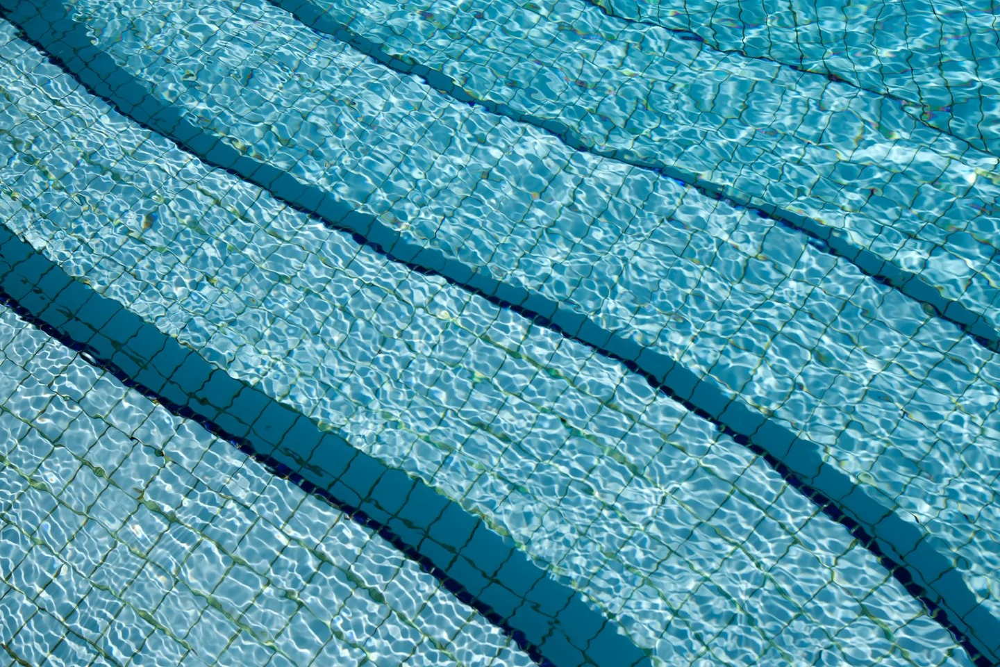 Piscina con agua azul para ilustrar por qué las piscinas huelen a cloro si están sucias.