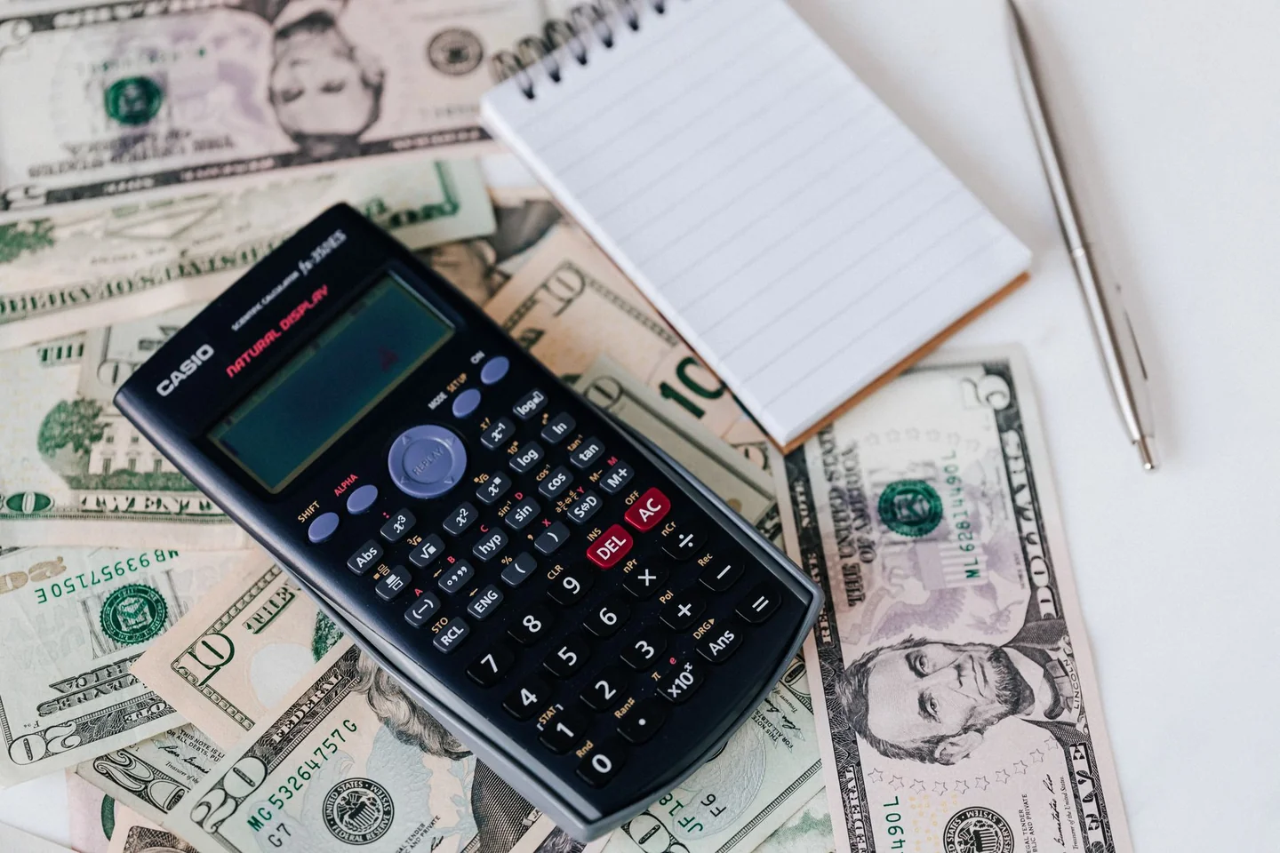 Imagen ilustrativa sobre cuánto dinero necesitas para irte de vacaciones sin deuda, con una calculadora y presupuesto de viaje sobre una mesa.