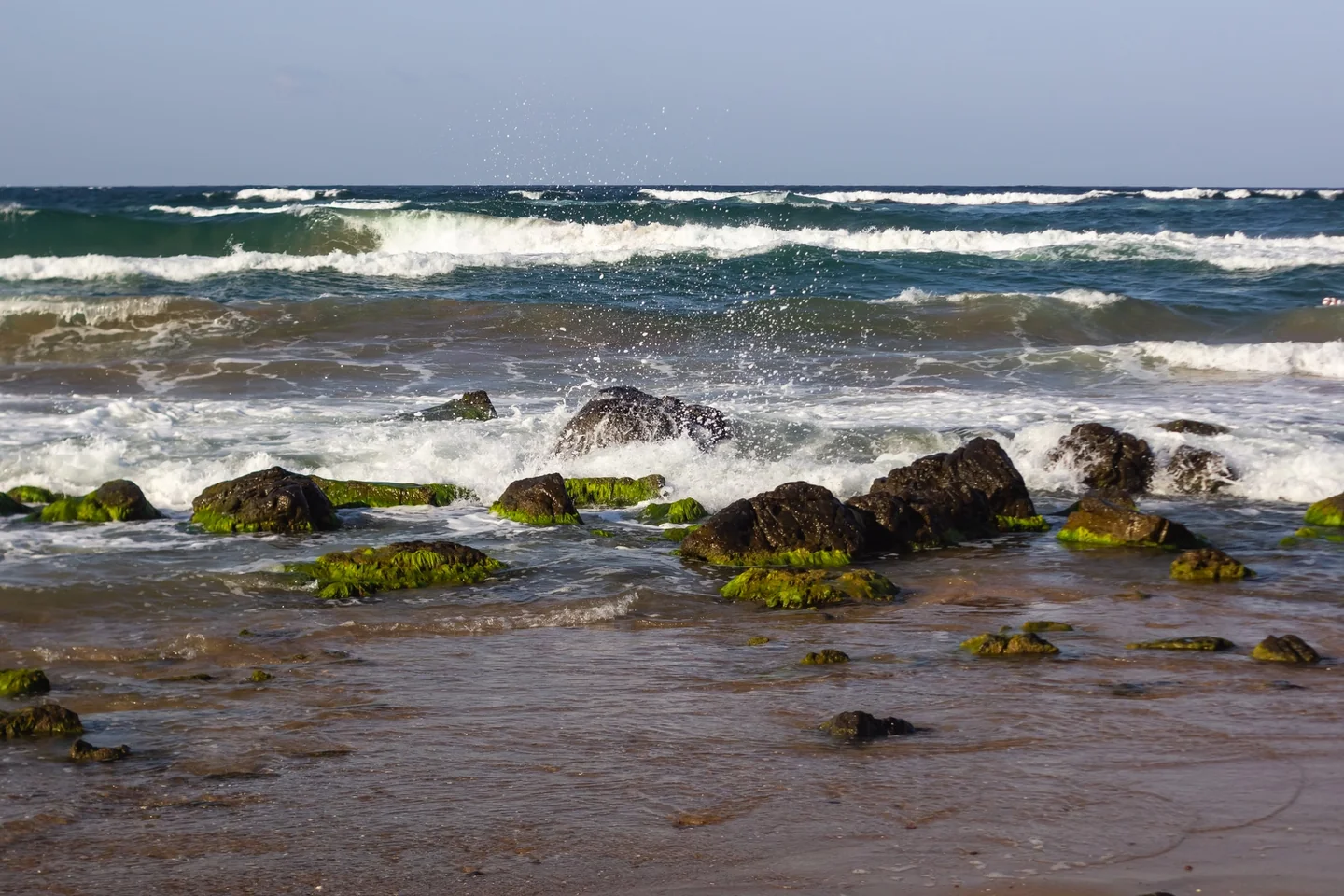 olas rompiendo en la orilla para ilustrar por qué las olas llegan paralelas a la playa