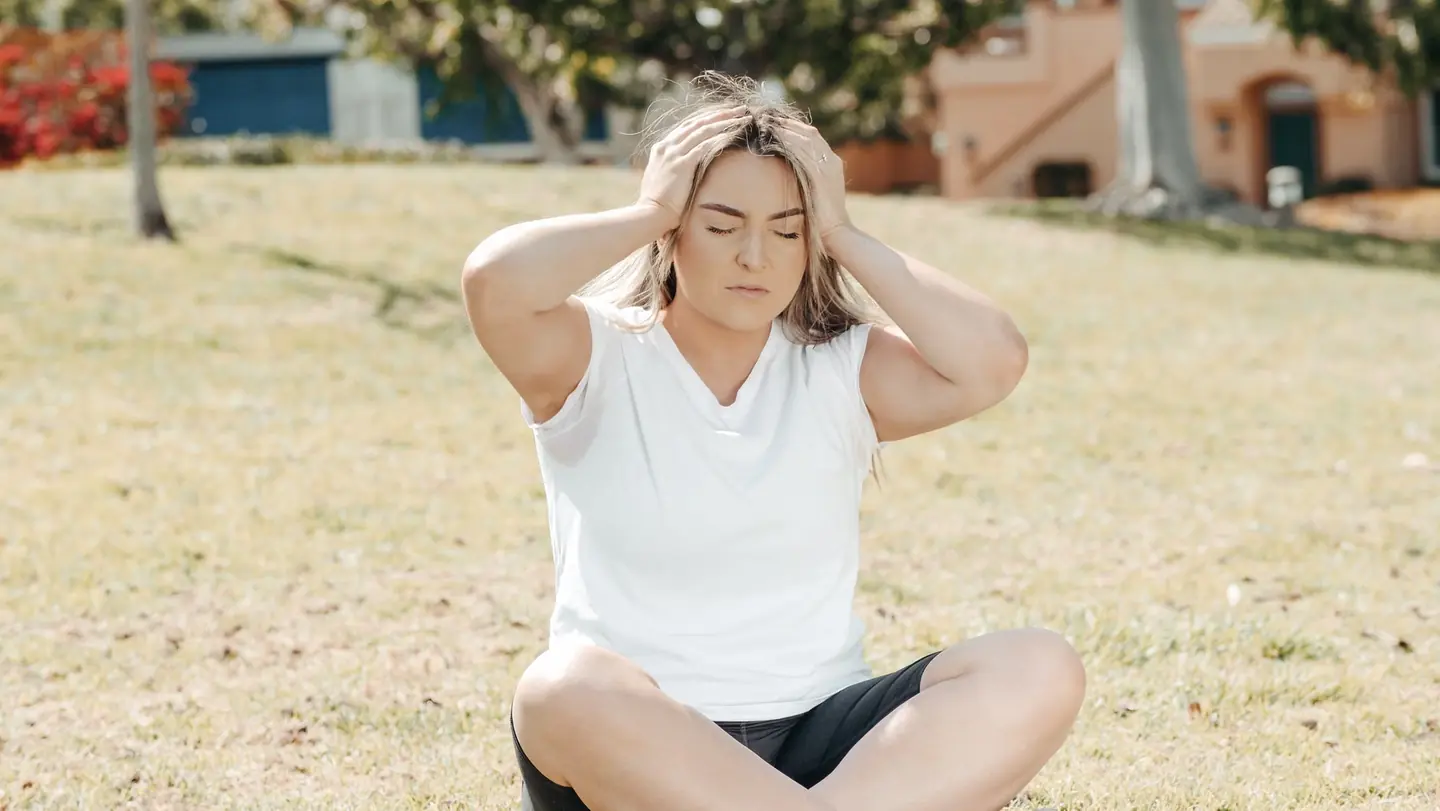 Mujer con expresión de dolor de cabeza para ilustrar migraña y calor por qué empeora en verano