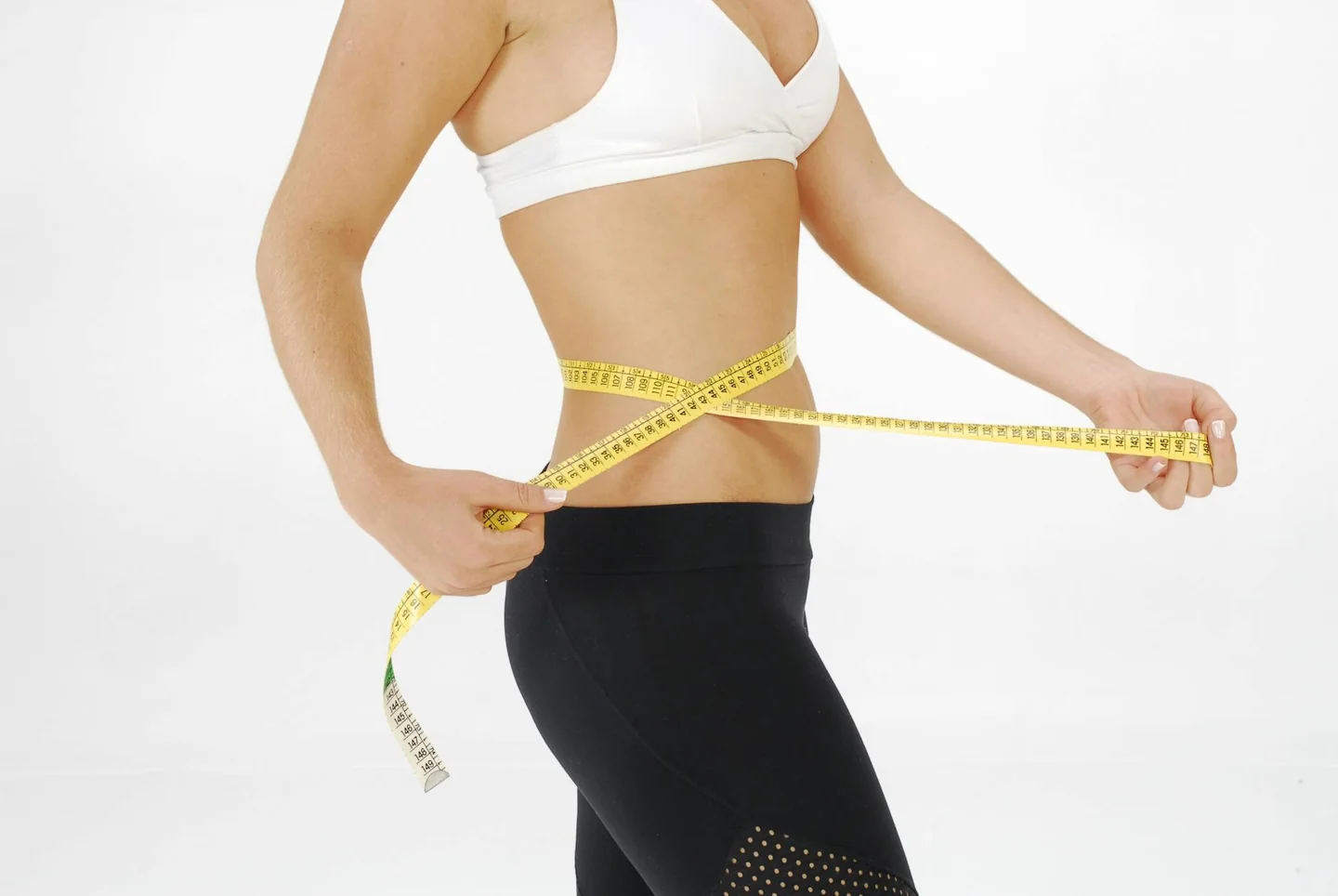 Mujer midiéndose la cintura para ilustrar por qué las dietas bikini vuelven cada junio