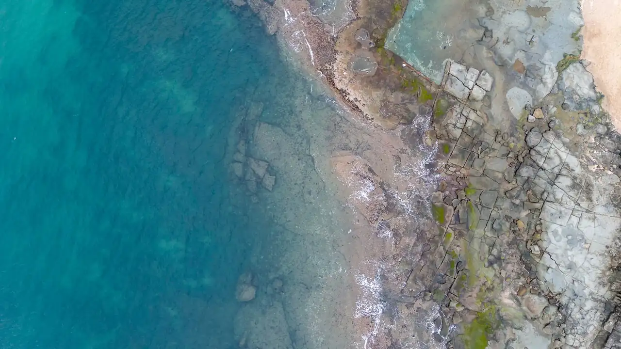 Imagen aérea para explicar por qué el mar es turquesa, con agua somera, arena blanca y arrecife