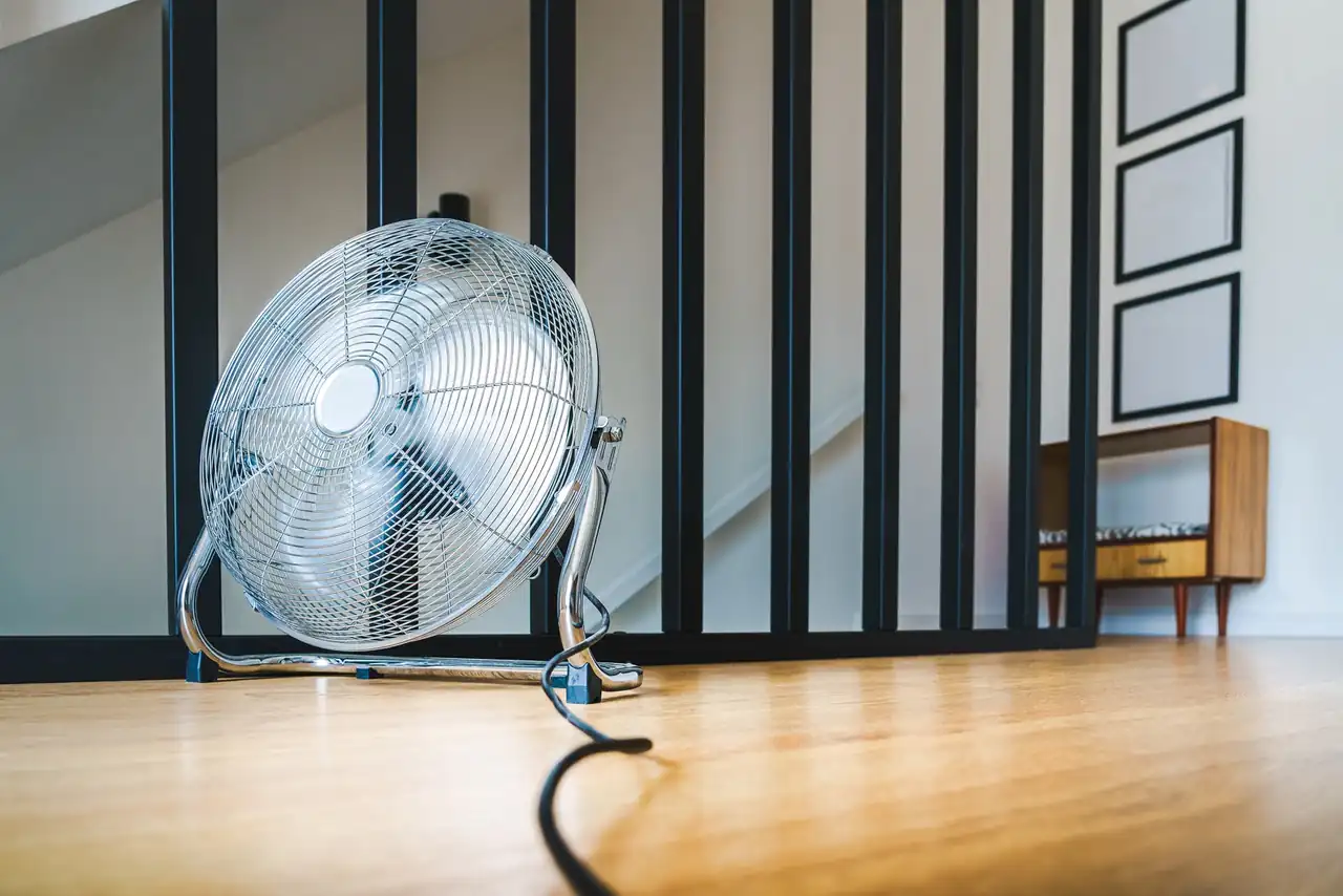 Ventilador colocado cerca de una ventana abierta para expulsar el calor de la habitación