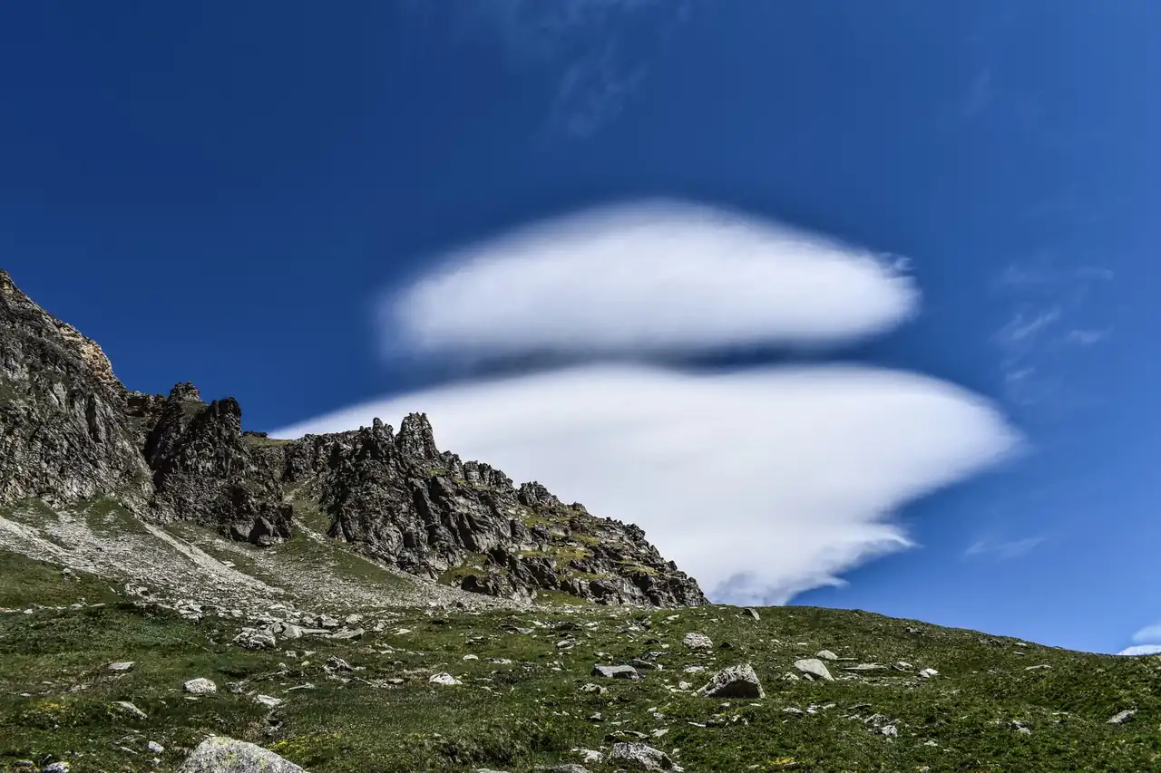 Nubes lenticulares en verano sobre una cordillera bajo un cielo azul