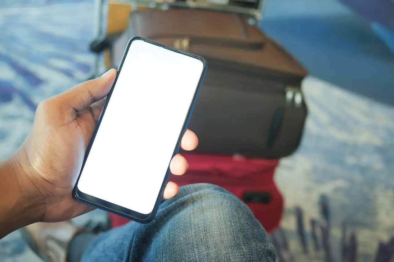 Persona comprobando la ubicación de un AirTag que tarda en actualizarse junto a una maleta