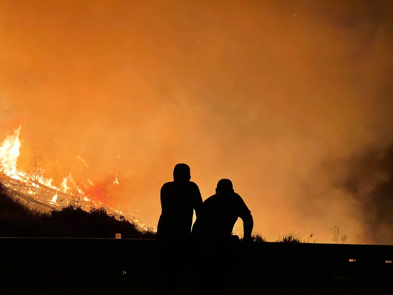Persona consulta en su móvil una alerta ES-Alert por incendios mientras se prepara para evacuar