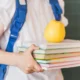 chico lleva manzana con libros
