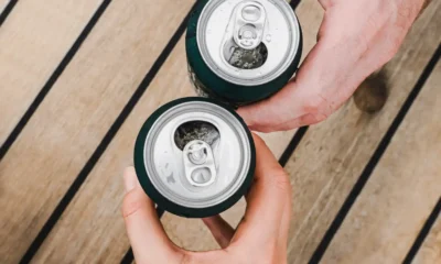 manos con latas birra mesa