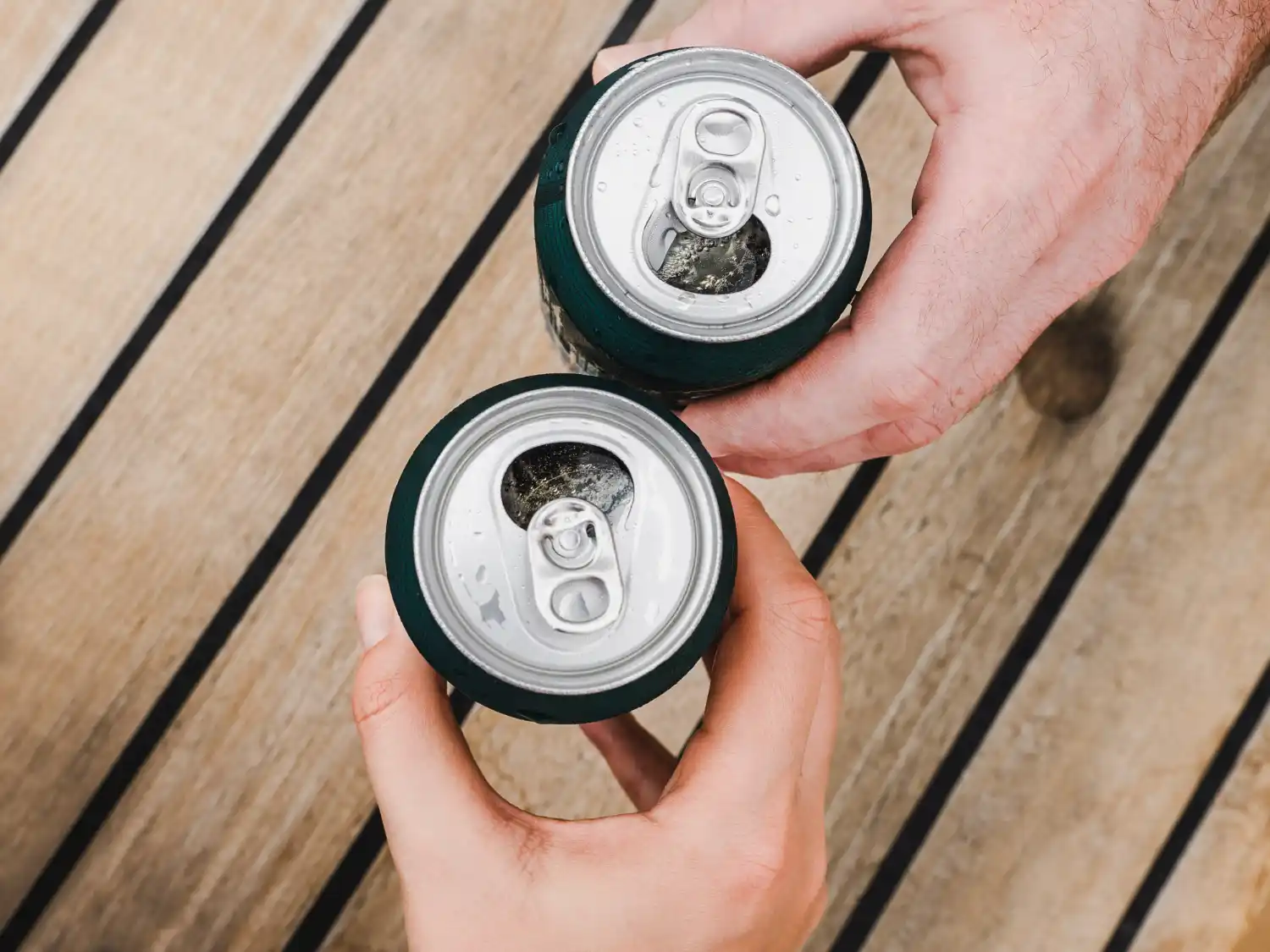 manos con latas birra mesa