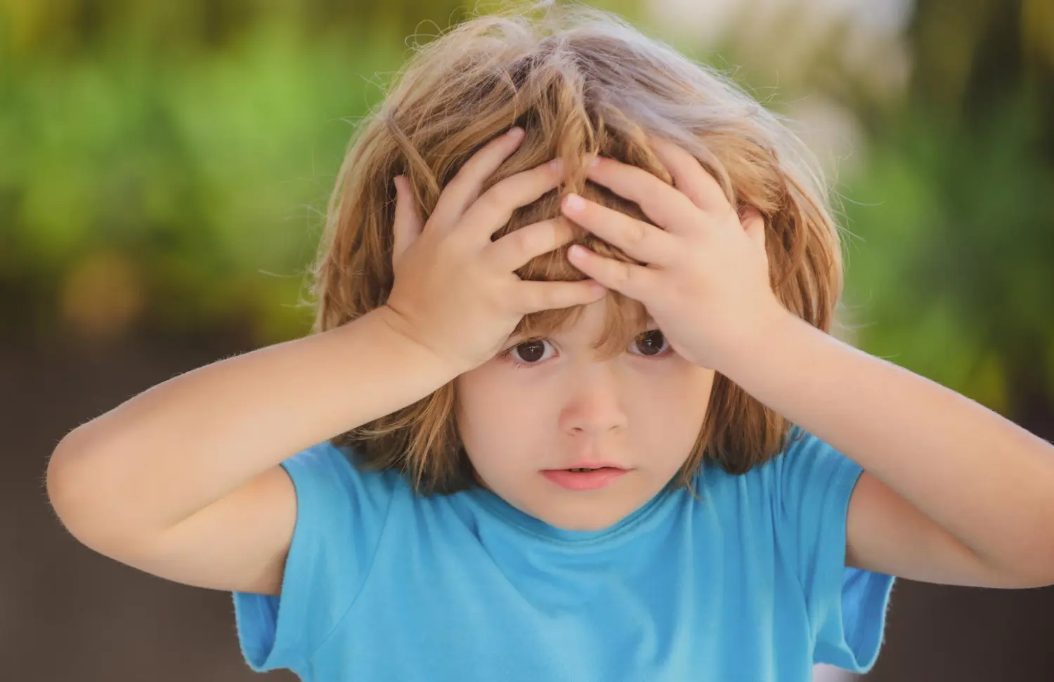 niño se mete manos en la cabeza