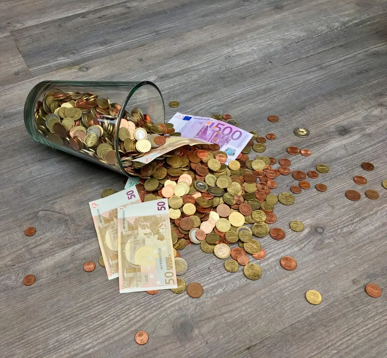 Hucha con monedas y billetes para ilustrar la decisión de ahorrar o invertir con tipos altos