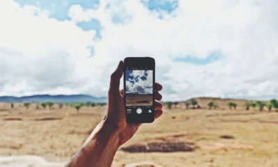 Una persona sostiene un teléfono bajo el cielo despejado para establecer la conexión satelital del móvil