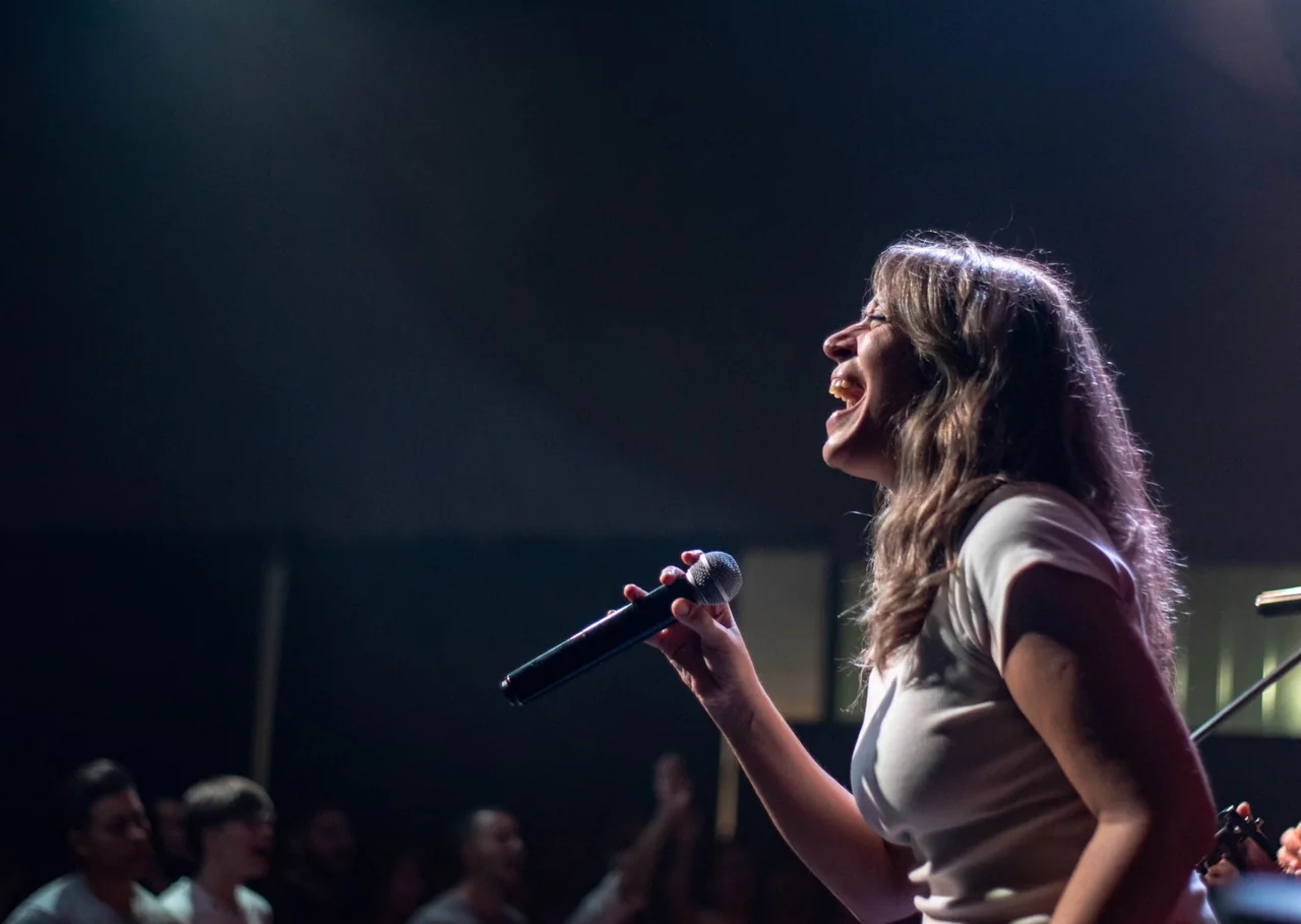 Cantante ante el micrófono durante una actuación, una escena que ilustra el debate sobre el playback en conciertos