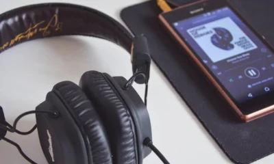 Teléfono con una aplicación de música abierta y auriculares, una escena que ilustra por qué algunas canciones dejan de aparecer en Spotify