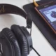 Teléfono con una aplicación de música abierta y auriculares, una escena que ilustra por qué algunas canciones dejan de aparecer en Spotify