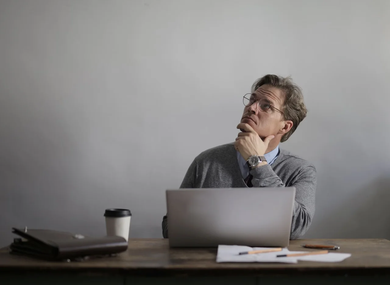 Profesional pensativo ante el ordenador, una escena asociada al síndrome del impostor en el trabajo
